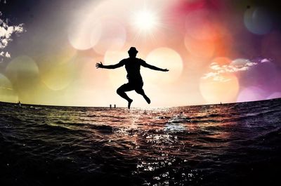 Silhouette of girl jumping in sky at sunset