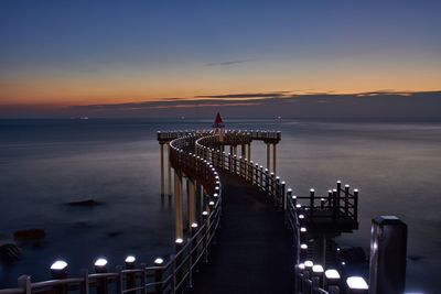 Pier over sea against sky at sunset