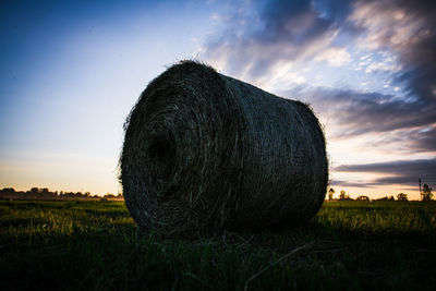 Hay bales on field against sky during sunset