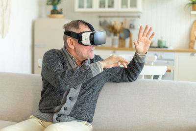 Young woman using mobile phone while sitting on sofa at home