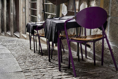 Empty chairs and tables at sidewalk cafe against building