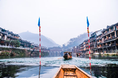 Wooden boat in lake against buildings