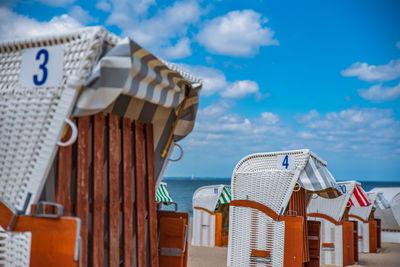 Hooded chairs on beach against blue sky