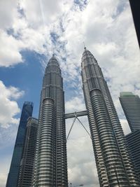 Low angle view of petronas twin towers against cloudy sky