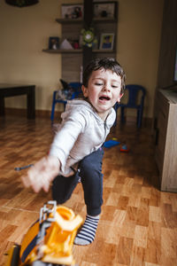 Upset little boy trowing toy car to the floor at home