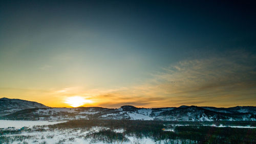 Scenic view of snowcapped mountains against sky during sunset