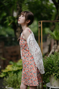 Young woman standing against plants