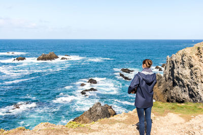 Man standing on rock formation in sea