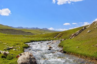 Scenic view of stream amidst mountains against sky