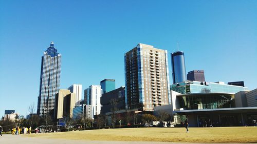 Low angle view of suntrust plaza by buildings against clear blue sky on sunny day