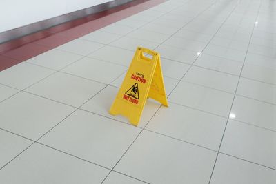 High angle view of warning sign on tiled floor