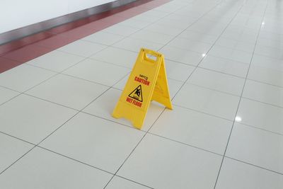 High angle view of arrow sign on tiled floor