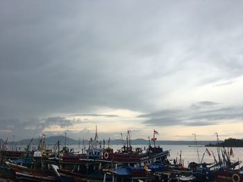 Boats moored at harbor against sky