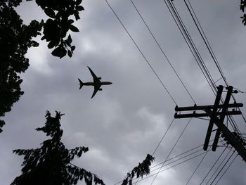 Directly below shot of silhouette airplane flying in cloudy sky