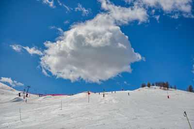 Panoramic view of people on snow covered land against blue sky