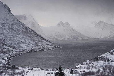 Scenic view of lake by snowcapped mountains against sky