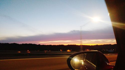 Cars on street against sky during sunset