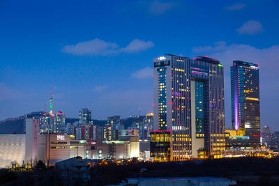 Illuminated buildings against blue sky at dusk