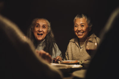 Happy senior female friends during dinner party at night