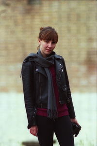 Portrait of young woman standing against wall