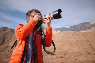 Caucasian woman landscape photographer with big lens and professional camera takes pictures 