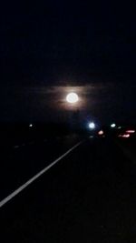 Illuminated road against sky at night