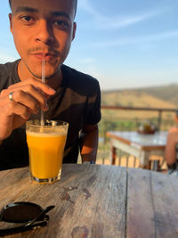 Portrait of man drinking juices in glasses on table