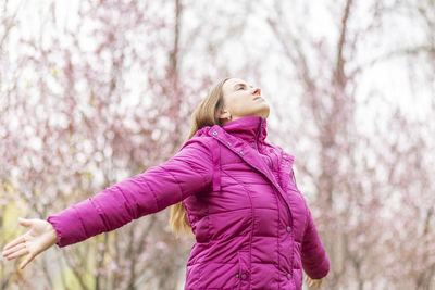 Young woman standing against trees