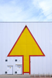 Yellow arrow on white facade