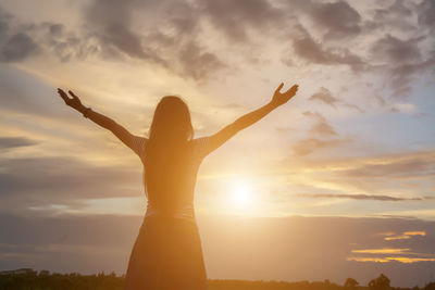 Low angle view of woman standing against sky during sunset