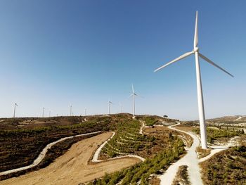 High angle view of road amidst land against sky, and windmills for electricity generation