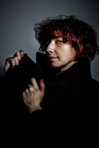 Portrait of redhead woman in jacket against gray background