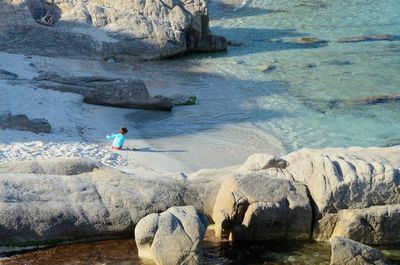 Rear view of playful child sitting on sea shore