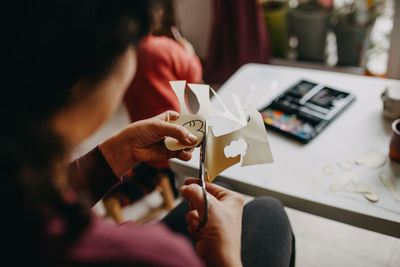 Midsection of woman cutting paper at home