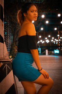 Side view of young woman standing at night