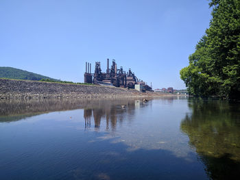 Buildings by lake against clear sky