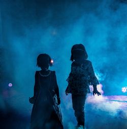 Rear view of couple standing at illuminated night