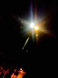 Low angle view of illuminated lighting equipment against sky at night