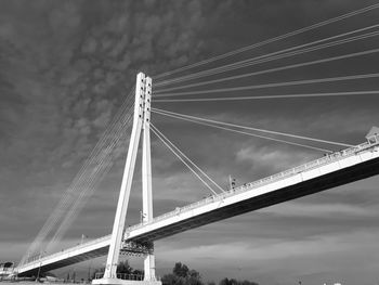 Low angle view of suspension bridge against cloudy sky