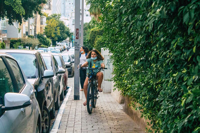 People on street amidst plants in city