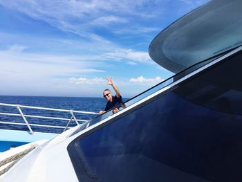 Man waving while traveling on yacht at sea against sky