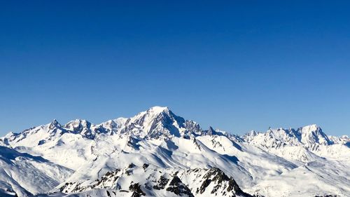 Scenic view of snowcapped mountains against clear blue sky