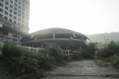 Road leading towards buildings against clear sky