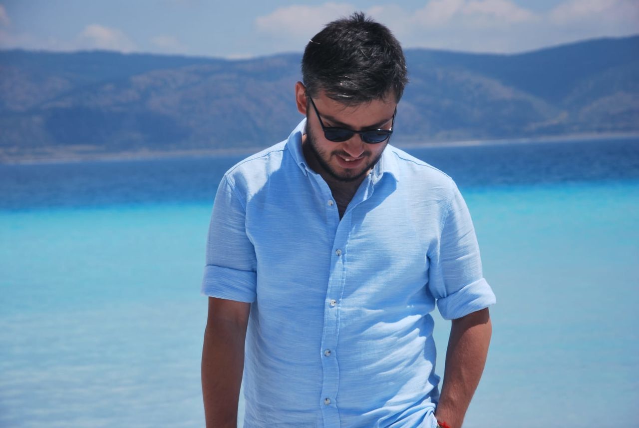 PORTRAIT OF YOUNG MAN STANDING BY SEA