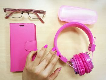Cropped hand of woman by pink headphones on table