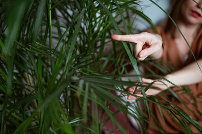 Woman shows her finger to the side against a background of green leaves