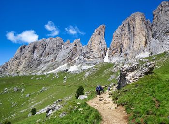 Panoramic view of people on rocks by mountains against sky