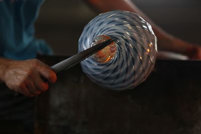 Cropped image of worker shaping glass in workshop