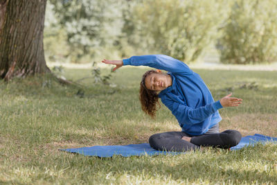 Side view of young woman sitting on field