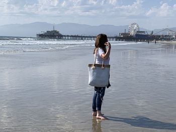 Full length of woman standing on beach against sea